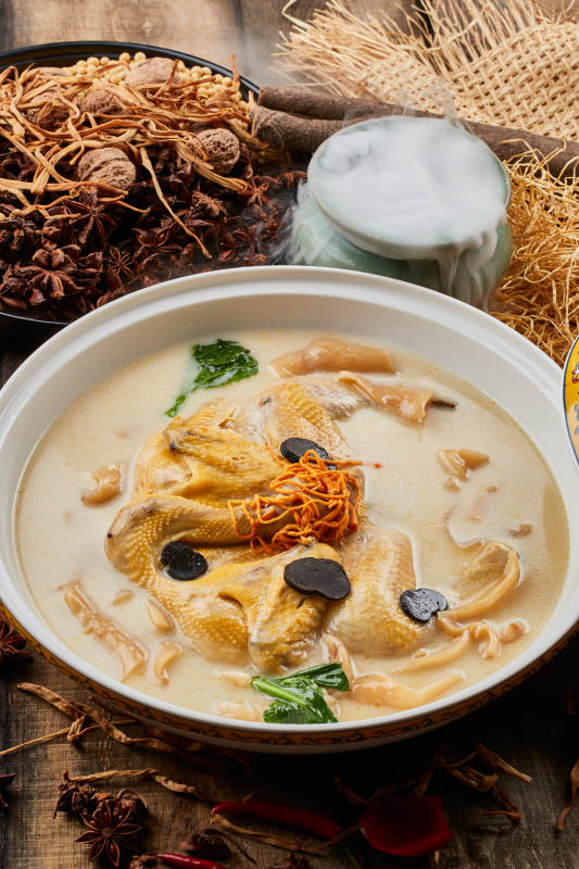 陈旧木板上的圆瓷汤盆装的花胶葛根炖柴鸡汤图片