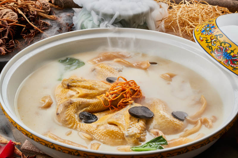 陈旧木板上的圆瓷汤盆装的花胶葛根炖柴鸡汤图片