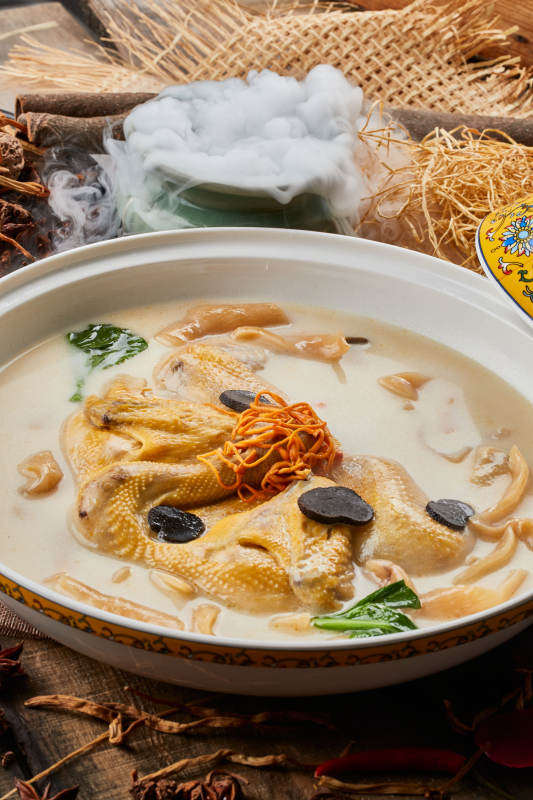 陈旧木板上的圆瓷汤盆装的花胶葛根炖柴鸡汤图片