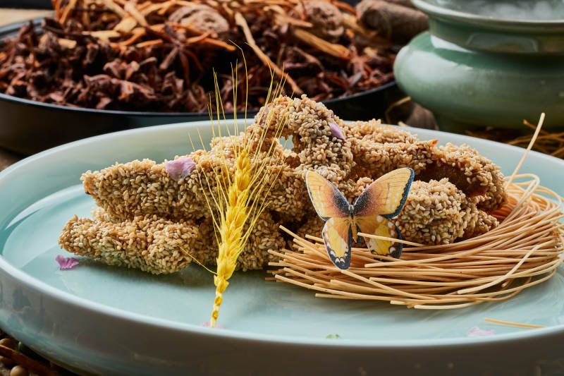 陈旧木板上的青釉圆瓷盘装的麻仁红薯图片