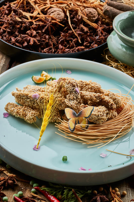 陈旧木板上的青釉圆瓷盘装的麻仁红薯图片