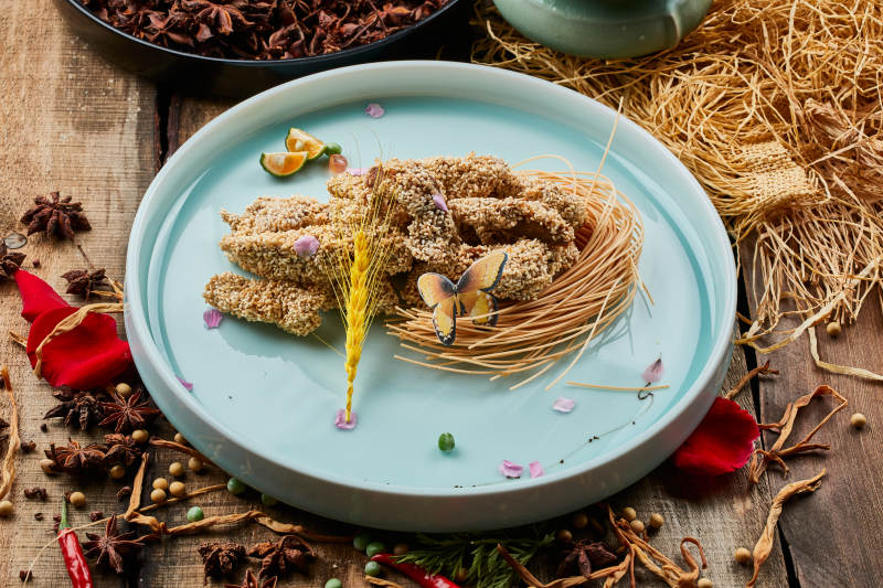 陈旧木板上的青釉圆瓷盘装的麻仁红薯图片