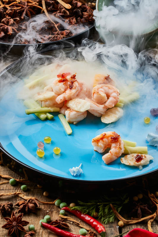 陈旧木板上的双色圆瓷盘装的芦笋山药焗虾仁图片