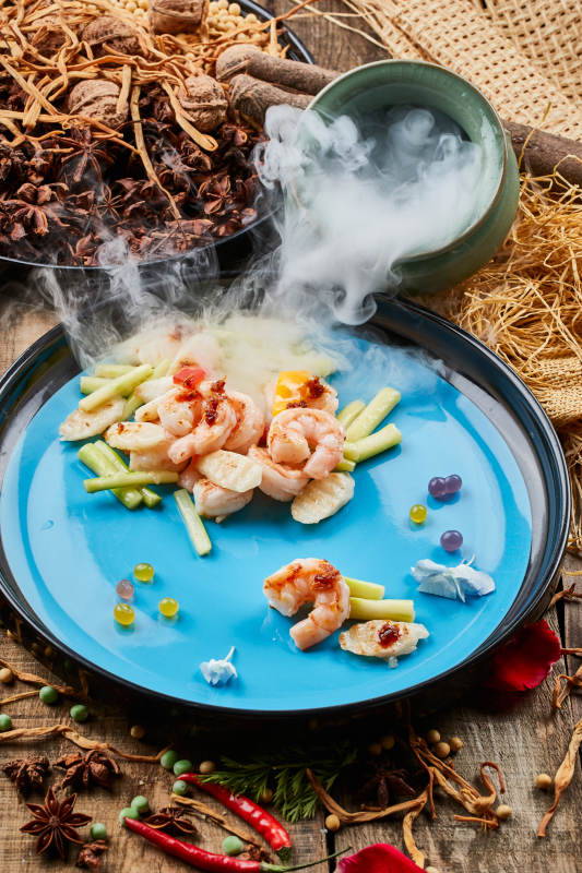 陈旧木板上的双色圆瓷盘装的芦笋山药焗虾仁图片