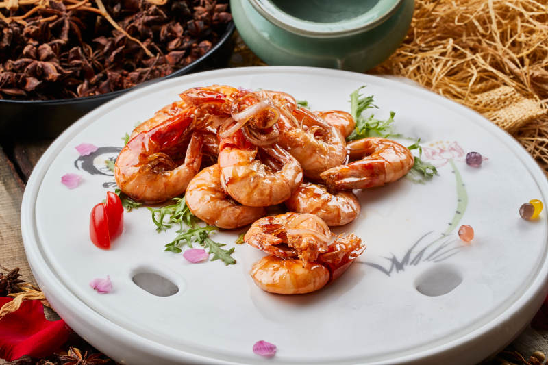 陈旧木板上的圆瓷盘装的广式油爆大虾图片