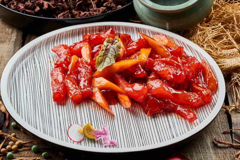 陈旧木板上的条纹圆瓷盘装的红烧蹄筋图片