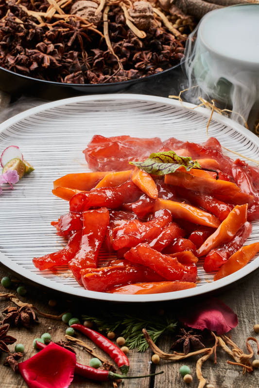 陈旧木板上的条纹圆瓷盘装的红烧蹄筋图片