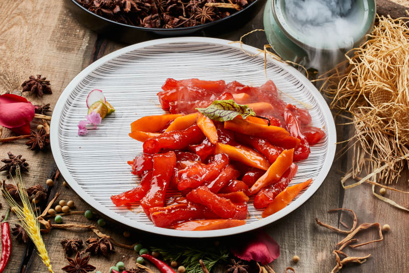 陈旧木板上的条纹圆瓷盘装的红烧蹄筋图片