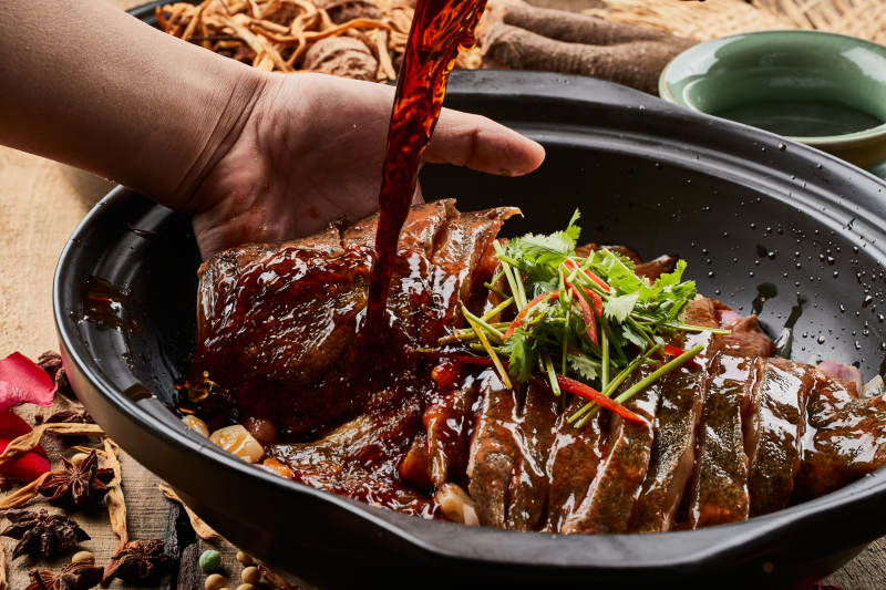 陈旧木板上的黑色砂锅装的浓汤生噘鲽鱼图片