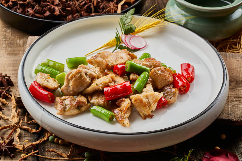 陈旧木板上的白色圆瓷盘装的杭椒鸡排图片