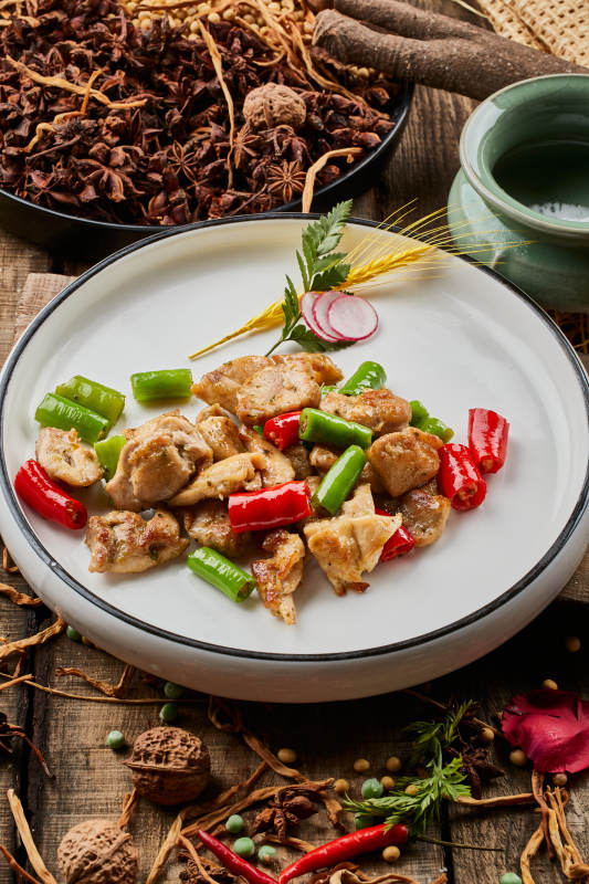 陈旧木板上的白色圆瓷盘装的杭椒鸡排图片