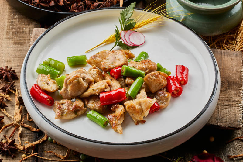 陈旧木板上的白色圆瓷盘装的杭椒鸡排图片