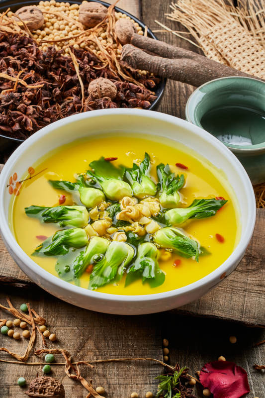 陈旧木板上的白瓷圆盘装的浓汤油菜烧菇片图片