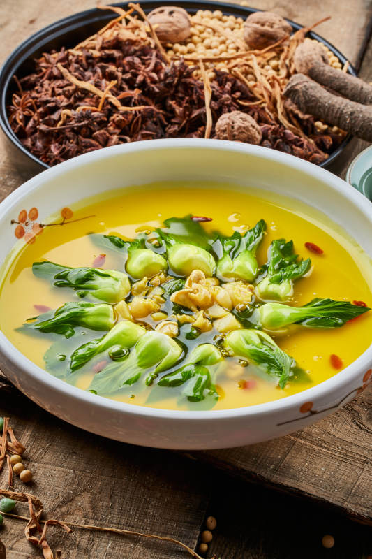 陈旧木板上的白瓷圆盘装的浓汤油菜烧菇片图片