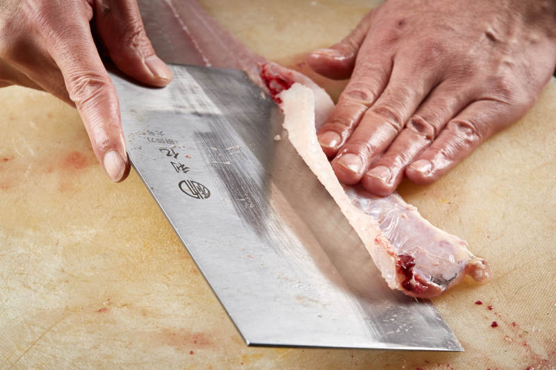 白色砧板上厨师用精湛的刀工展示生鱼片及鲜鱼料理切割分切的刀工图片