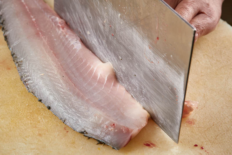 白色砧板上厨师用精湛的刀工展示生鱼片及鲜鱼料理切割分切的刀工图片