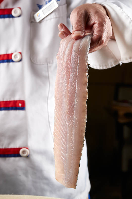 白色砧板上厨师用精湛的刀工展示生鱼片及鲜鱼料理切割分切的刀工图片