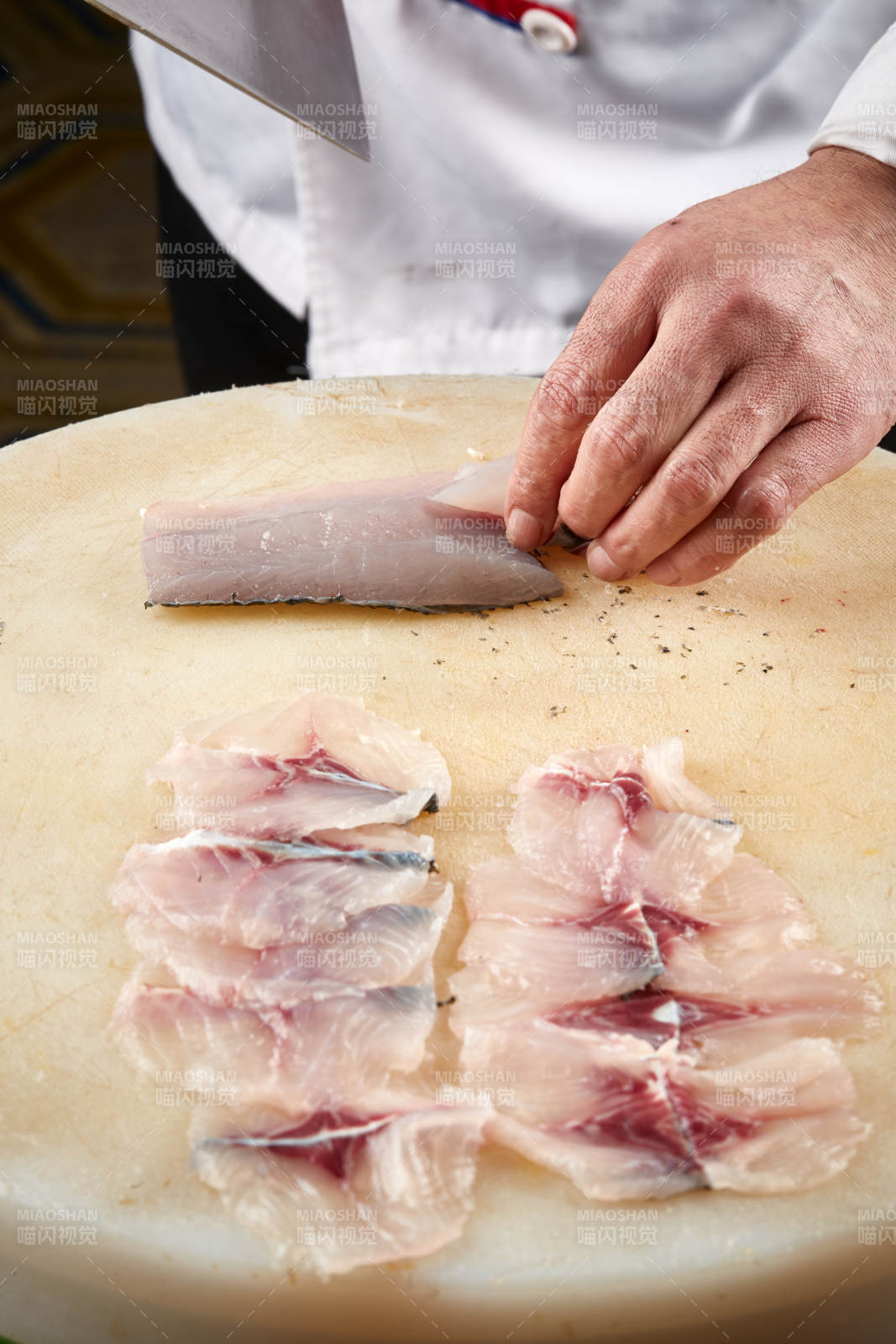 白色砧板上厨师用精湛的刀工展示生鱼片及鲜鱼料理切割分切的刀工图片