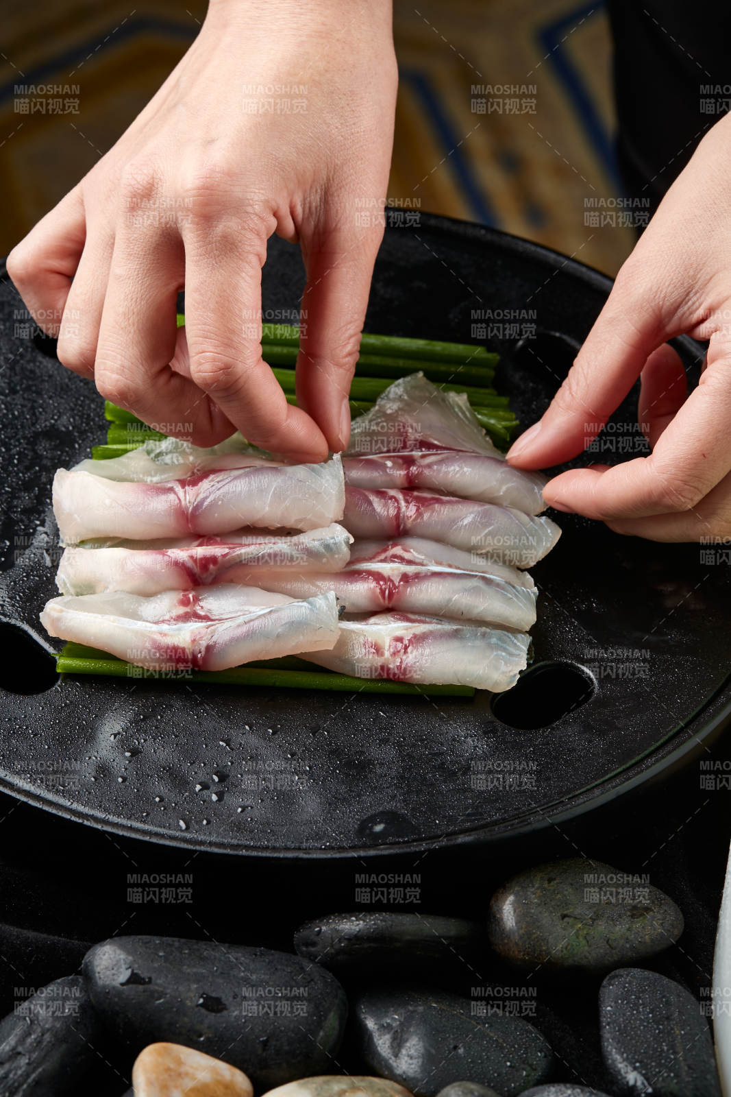 将晶莹白润的鲜鱼片码放在黑色的圆瓷盘上图片