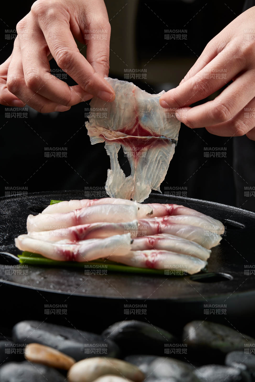 将晶莹白润的鲜鱼片码放在黑色的圆瓷盘上图片