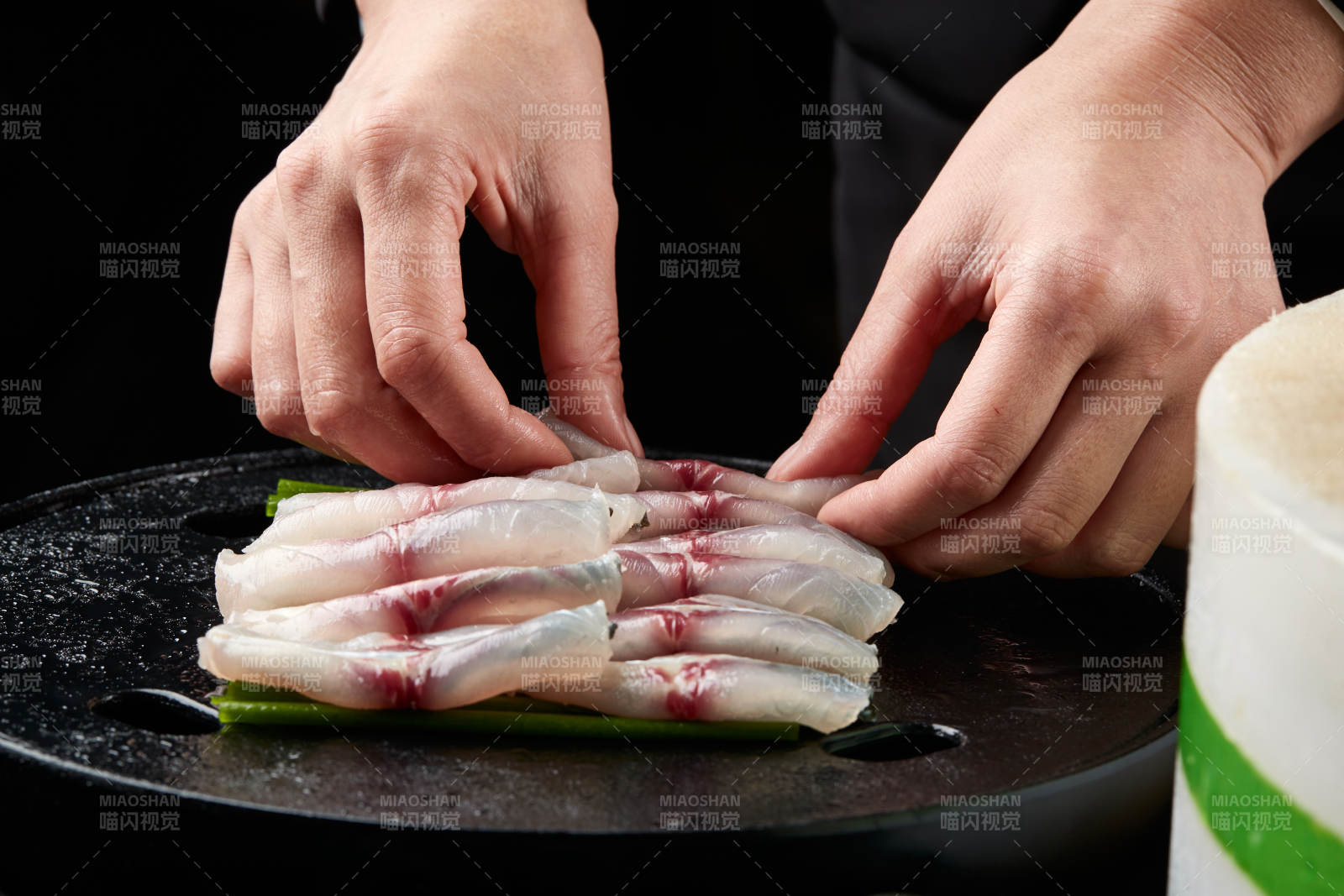 将晶莹白润的鲜鱼片码放在黑色的圆瓷盘上图片