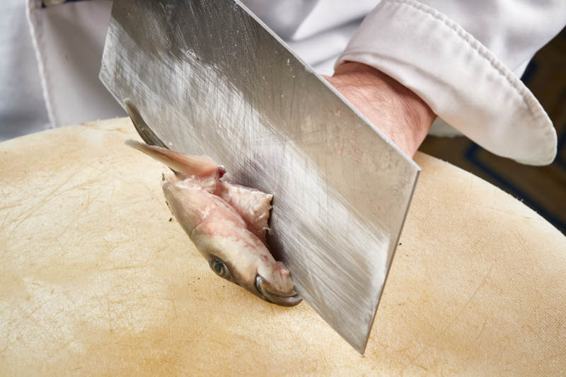 白色砧板上厨师用精湛的刀工展示生鱼片及鲜鱼料理切割分切的刀工图片