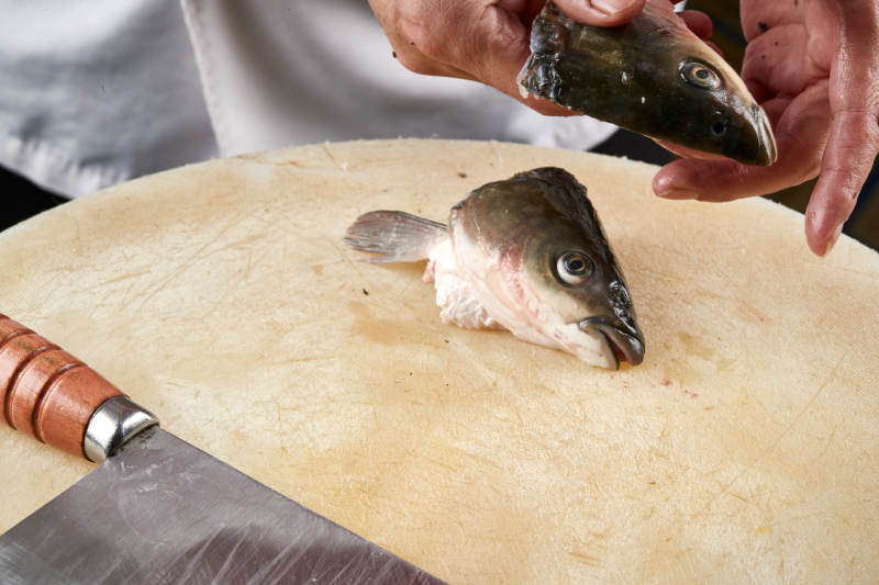 白色砧板上厨师用精湛的刀工展示生鱼片及鲜鱼料理切割分切的刀工图片