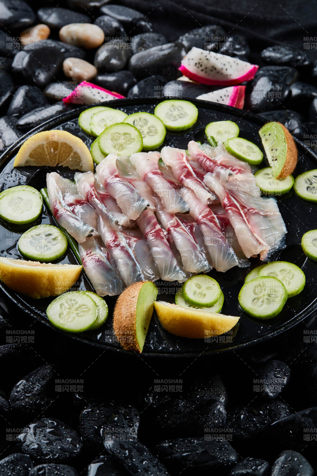 将晶莹白润的鲜鱼片码放在黑色的圆瓷盘上图片