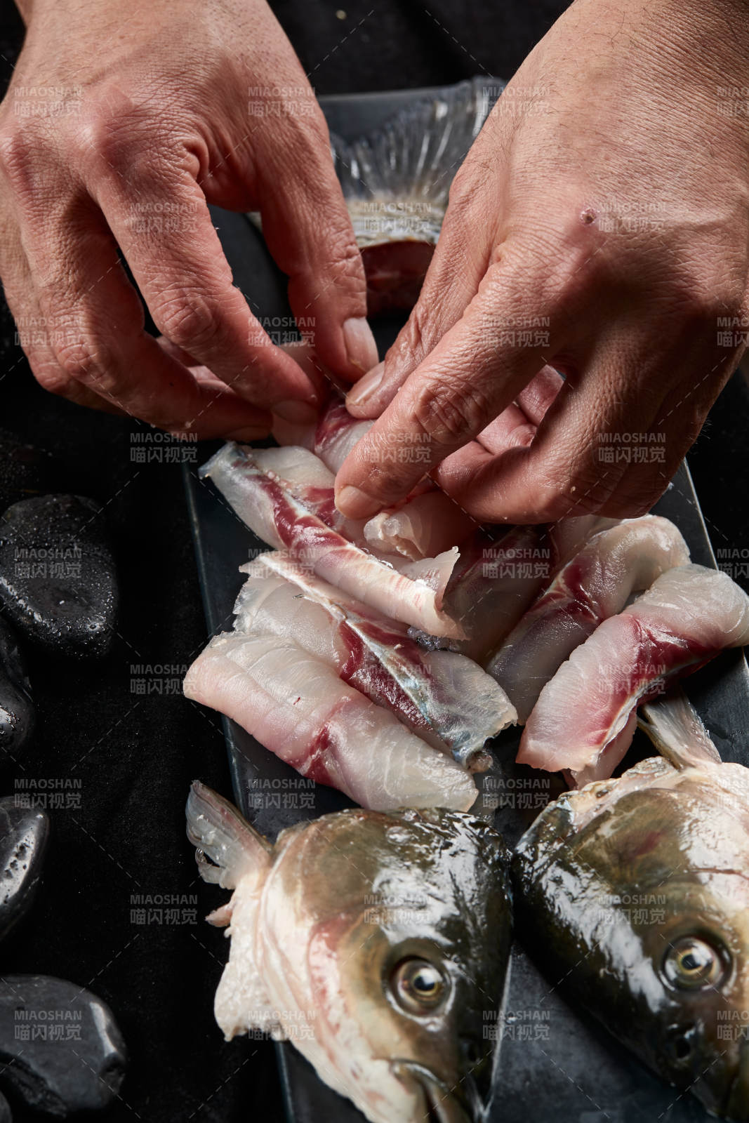 将晶莹白润的鲜鱼片码放在黑色的圆瓷盘上图片