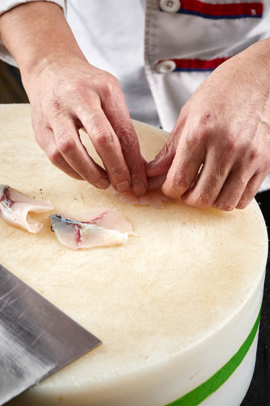 将晶莹白润的鲜鱼片码放在黑色的圆瓷盘上图片