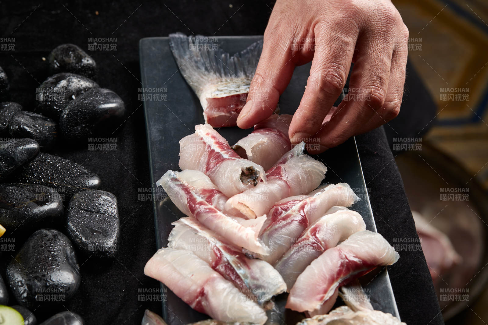 将晶莹白润的鲜鱼片码放在黑色的圆瓷盘上图片