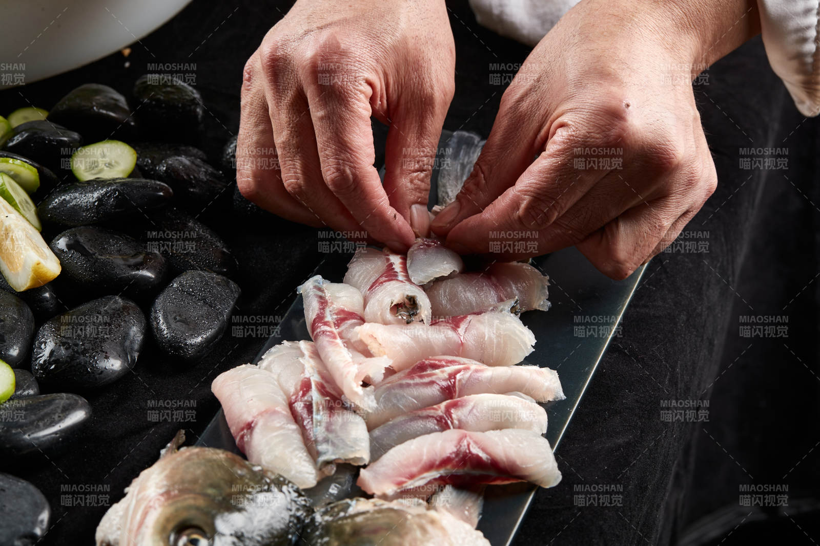 将晶莹白润的鲜鱼片码放在黑色的圆瓷盘上图片