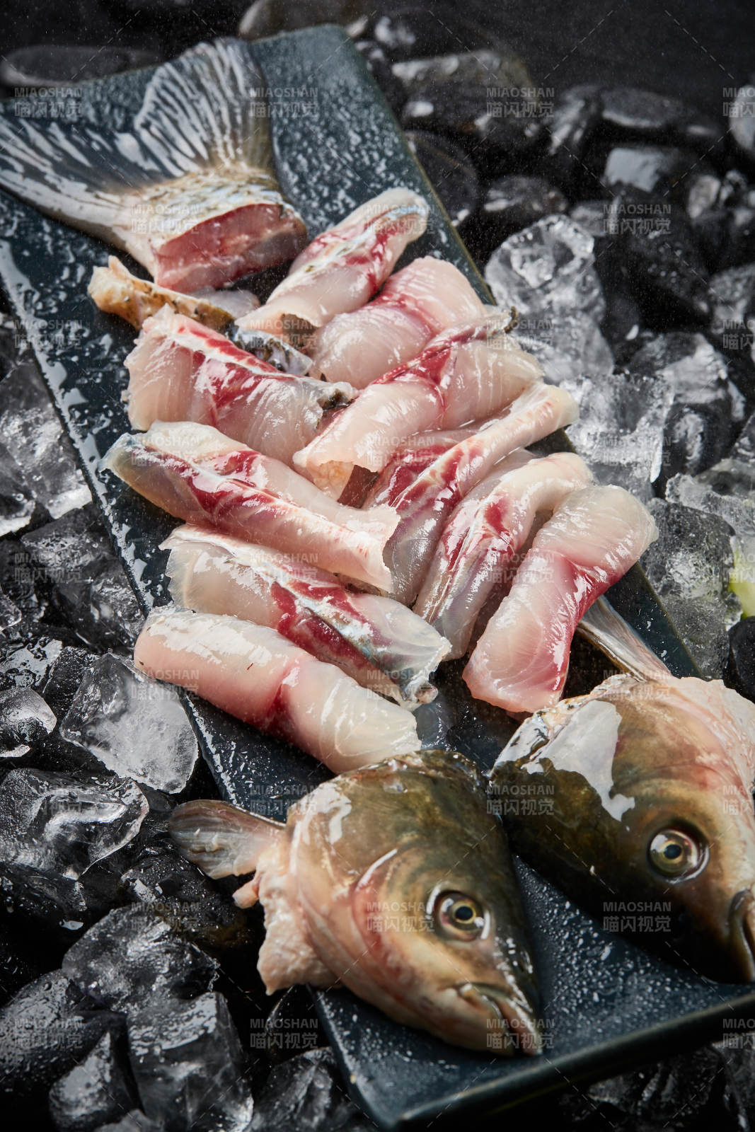 将晶莹白润的鲜鱼片码放在黑色的圆瓷盘上图片