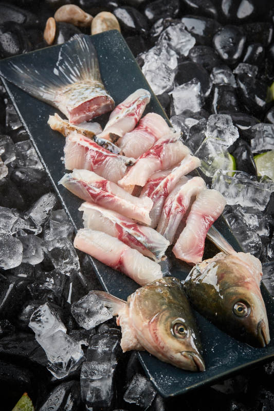 将晶莹白润的鲜鱼片码放在黑色的圆瓷盘上图片