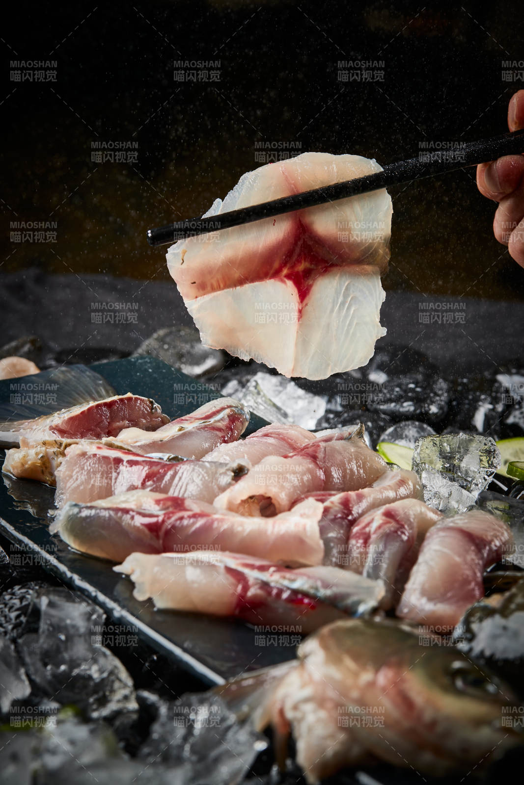 将晶莹白润的鲜鱼片码放在黑色的圆瓷盘上图片