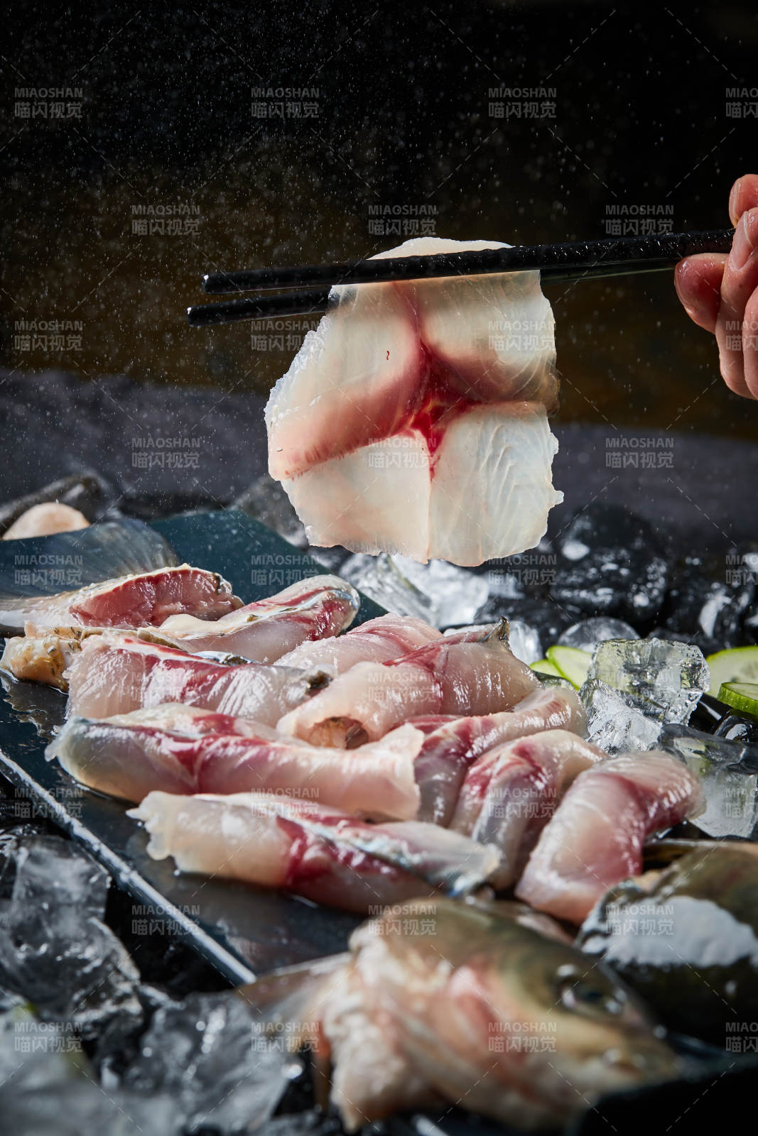 将晶莹白润的鲜鱼片码放在黑色的圆瓷盘上图片