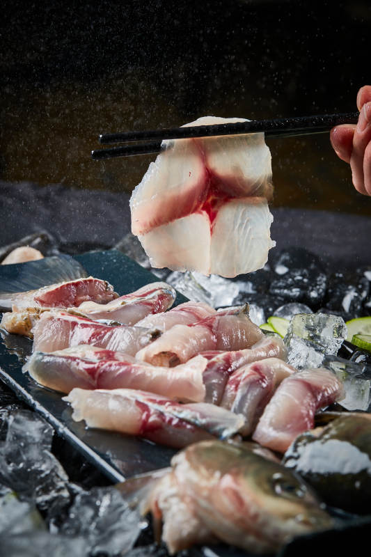 将晶莹白润的鲜鱼片码放在黑色的圆瓷盘上图片