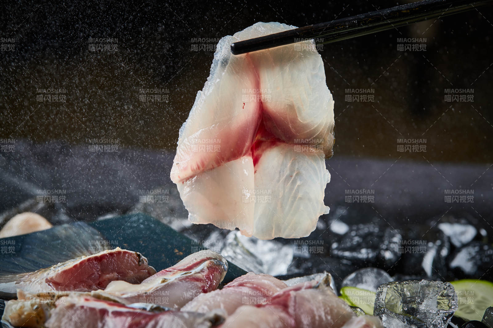 将晶莹白润的鲜鱼片码放在黑色的圆瓷盘上图片