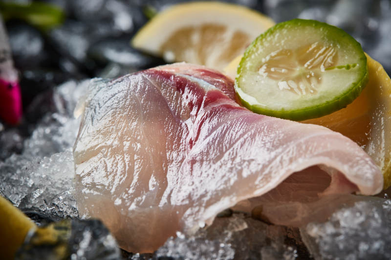 将晶莹白润的鲜鱼片码放在黑色的圆瓷盘上图片