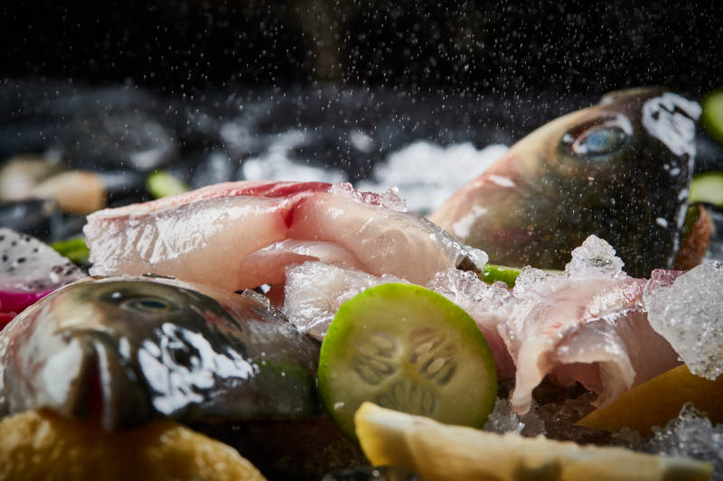 将晶莹白润的鲜鱼片码放在黑色的圆瓷盘上图片