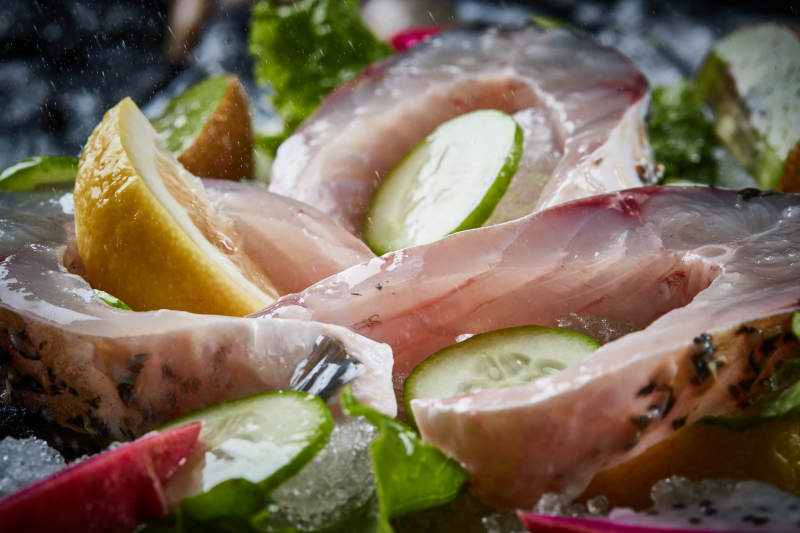 将晶莹白润的鲜鱼片码放在黑色的圆瓷盘上图片