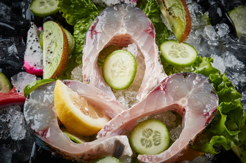 将晶莹白润的鲜鱼片码放在黑色的圆瓷盘上图片