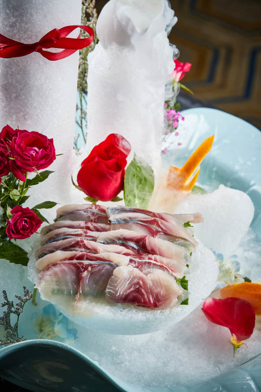 将晶莹白润的鲜鱼片码放在黑色的圆瓷盘上图片