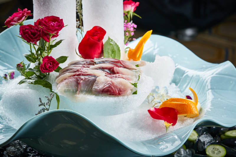 将晶莹白润的鲜鱼片码放在黑色的圆瓷盘上图片