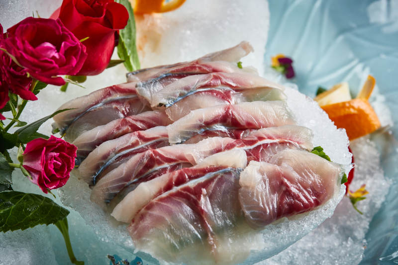 将晶莹白润的鲜鱼片码放在黑色的圆瓷盘上图片