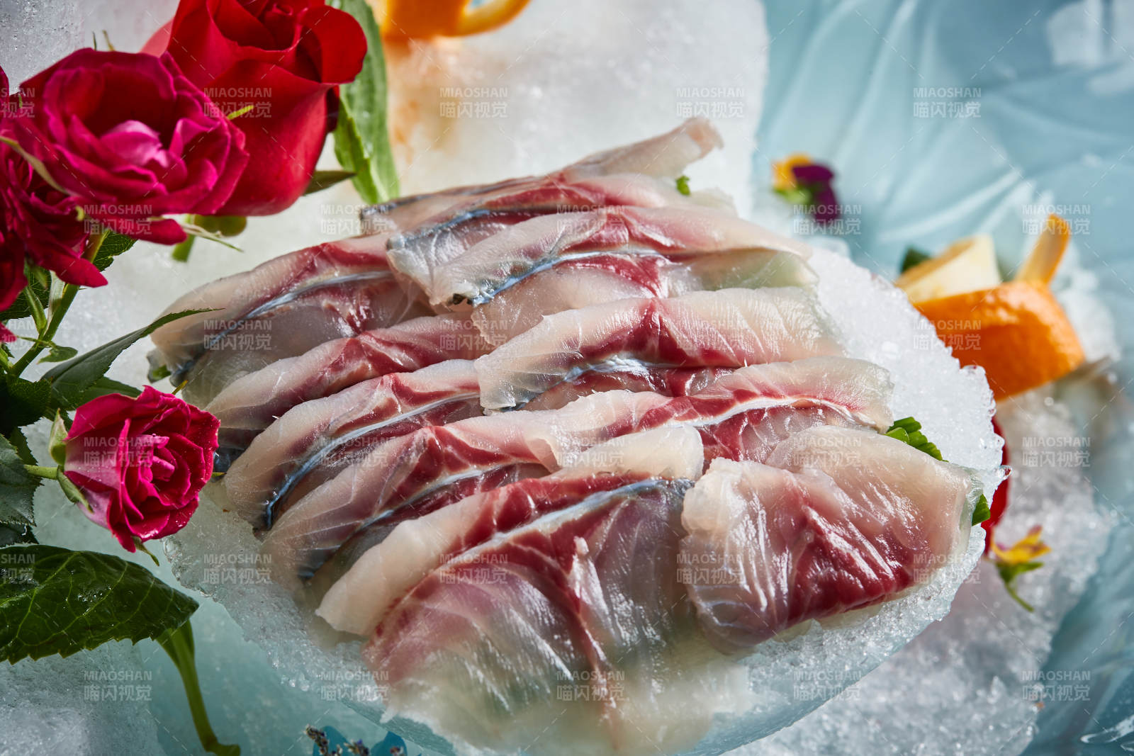 将晶莹白润的鲜鱼片码放在黑色的圆瓷盘上图片