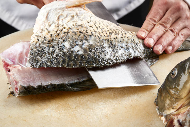 白色砧板上厨师用精湛的刀工展示生鱼片及鲜鱼料理切割分切的刀工图片