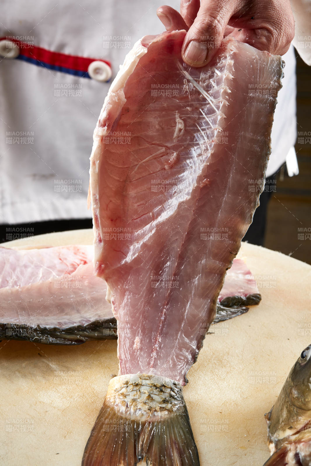 白色砧板上厨师用精湛的刀工展示生鱼片及鲜鱼料理切割分切的刀工图片