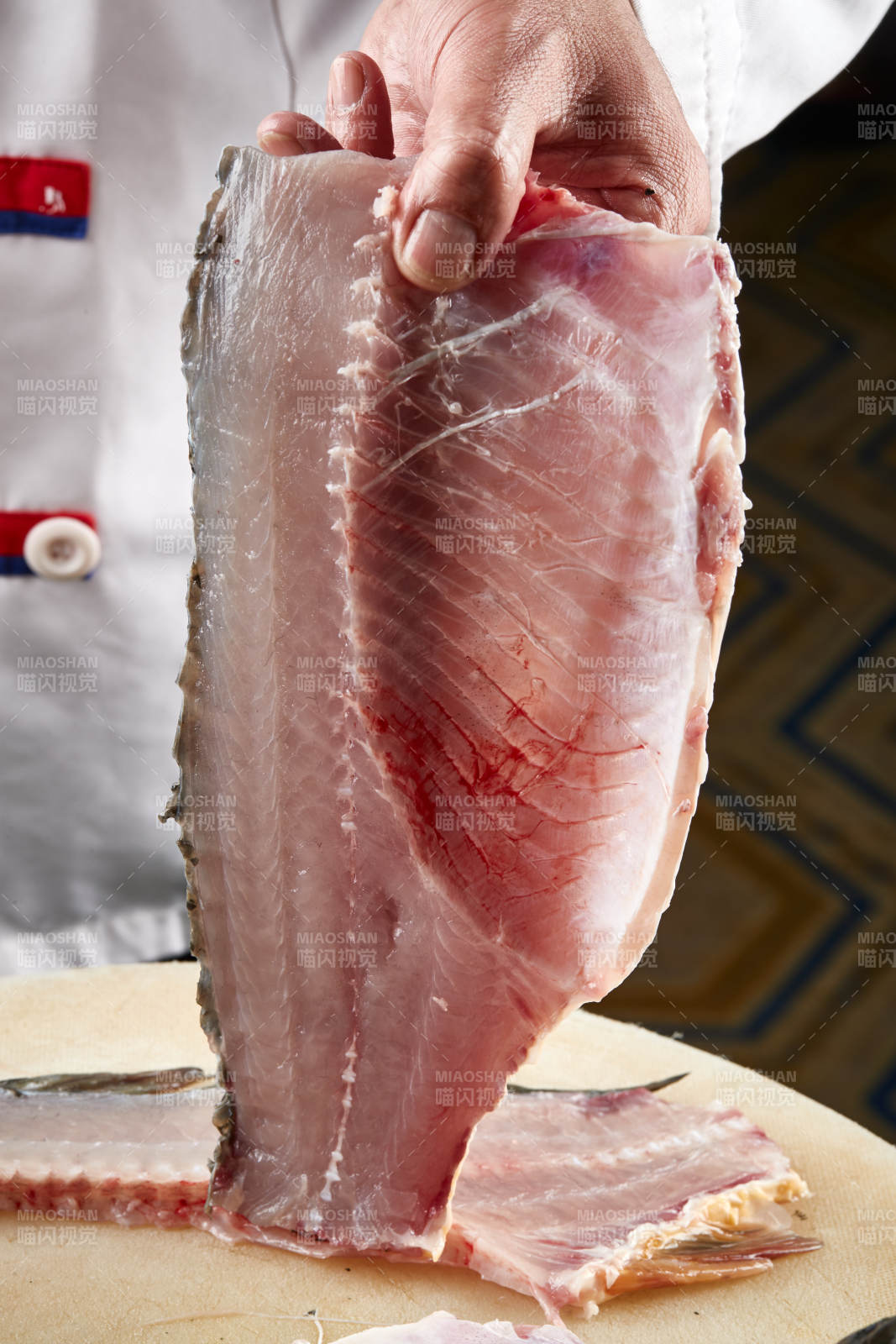 白色砧板上厨师用精湛的刀工展示生鱼片及鲜鱼料理切割分切的刀工图片