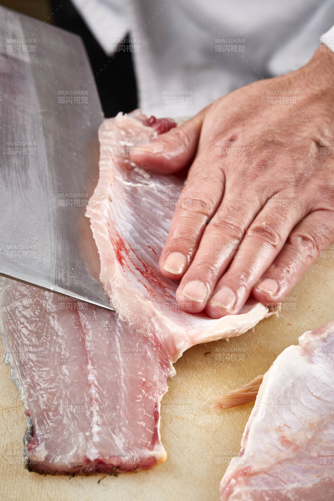 白色砧板上厨师用精湛的刀工展示生鱼片及鲜鱼料理切割分切的刀工图片